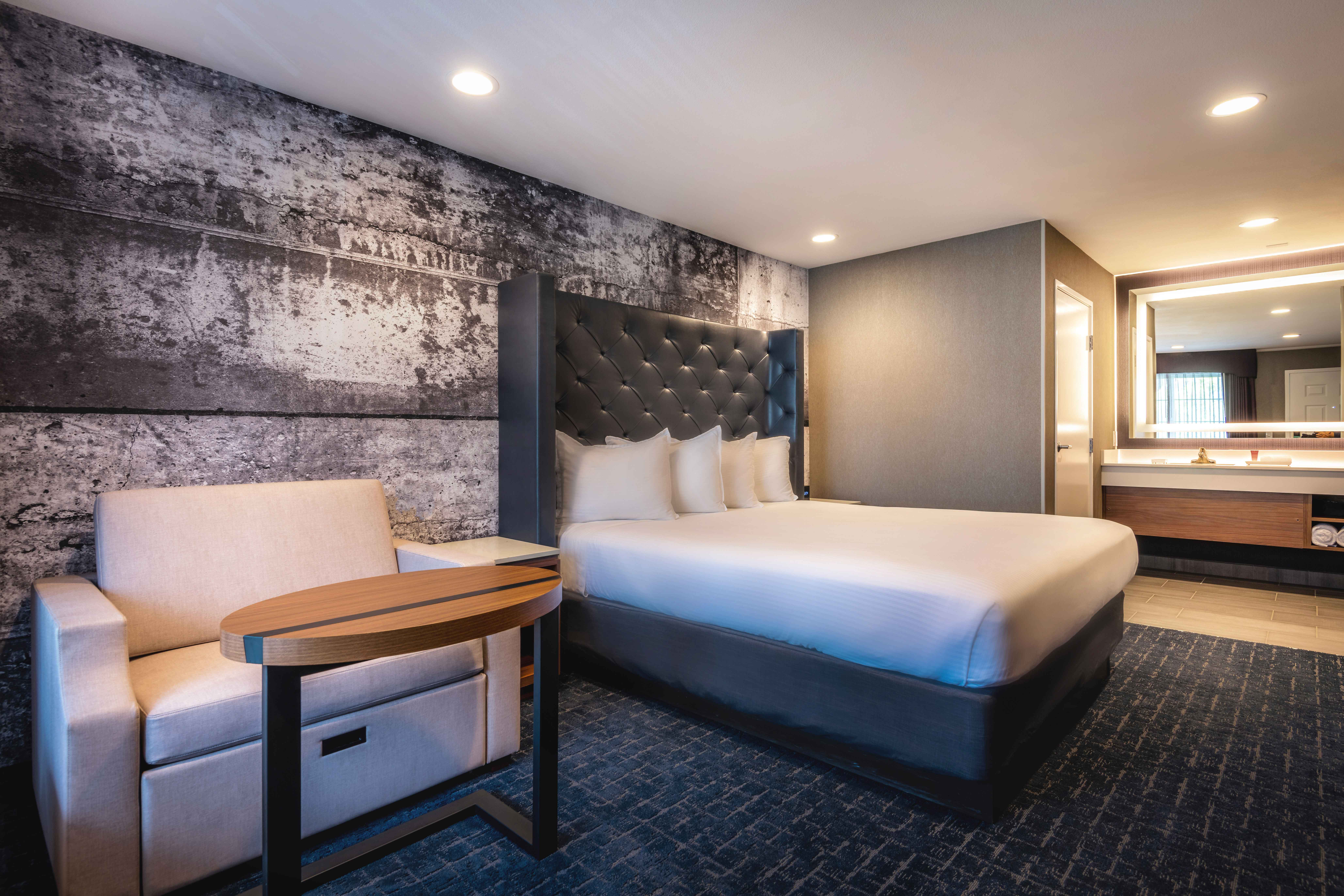 A hotel room with a bed, sofa, desk, and bathroom in the background.