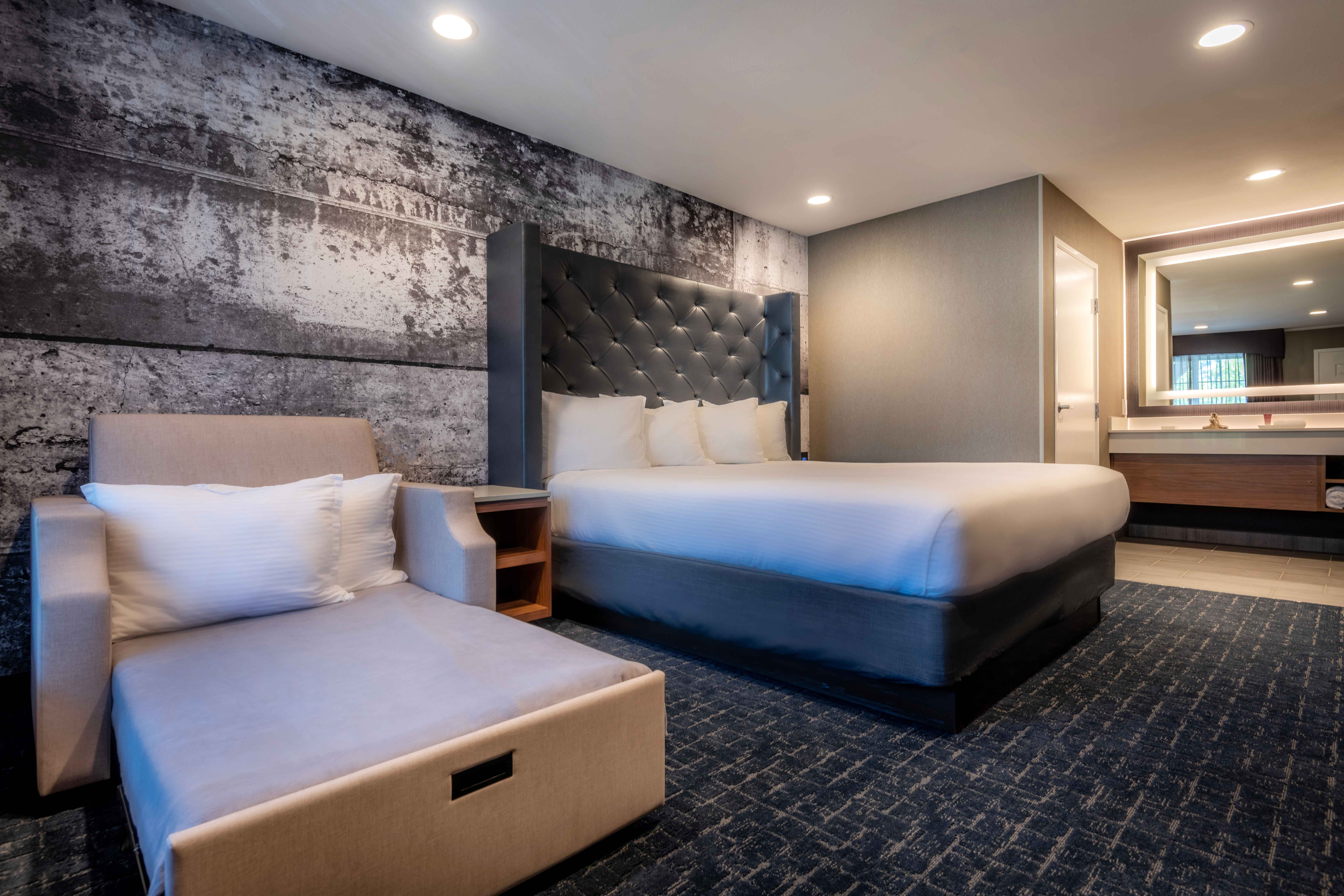 A wide view of a hotel room with a king bed, sofa bed, and bathroom.