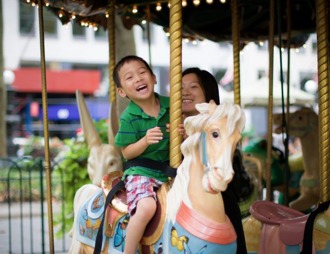 boy and mom laughing on a carousel
