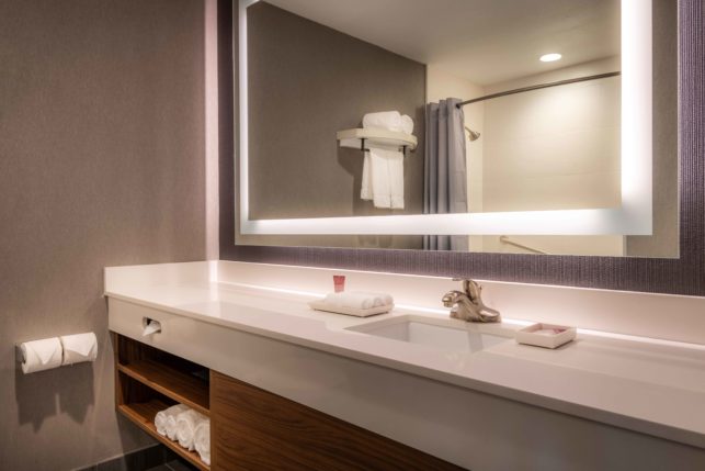bathroom vanity with custom bath amenities and LED mirror