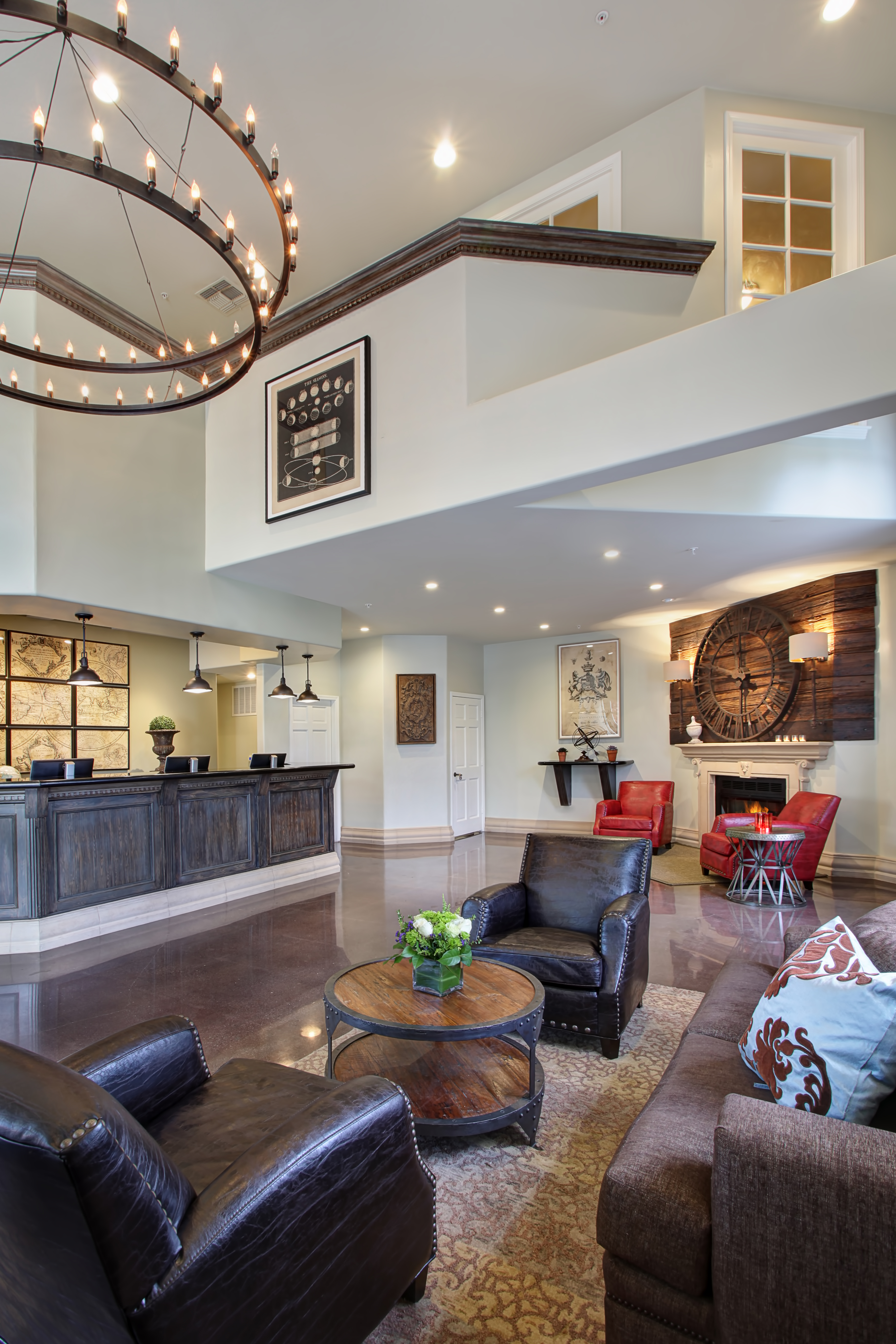 A hotel lobby with a high ceiling, a reception desk, a seating area, and a fireplace.